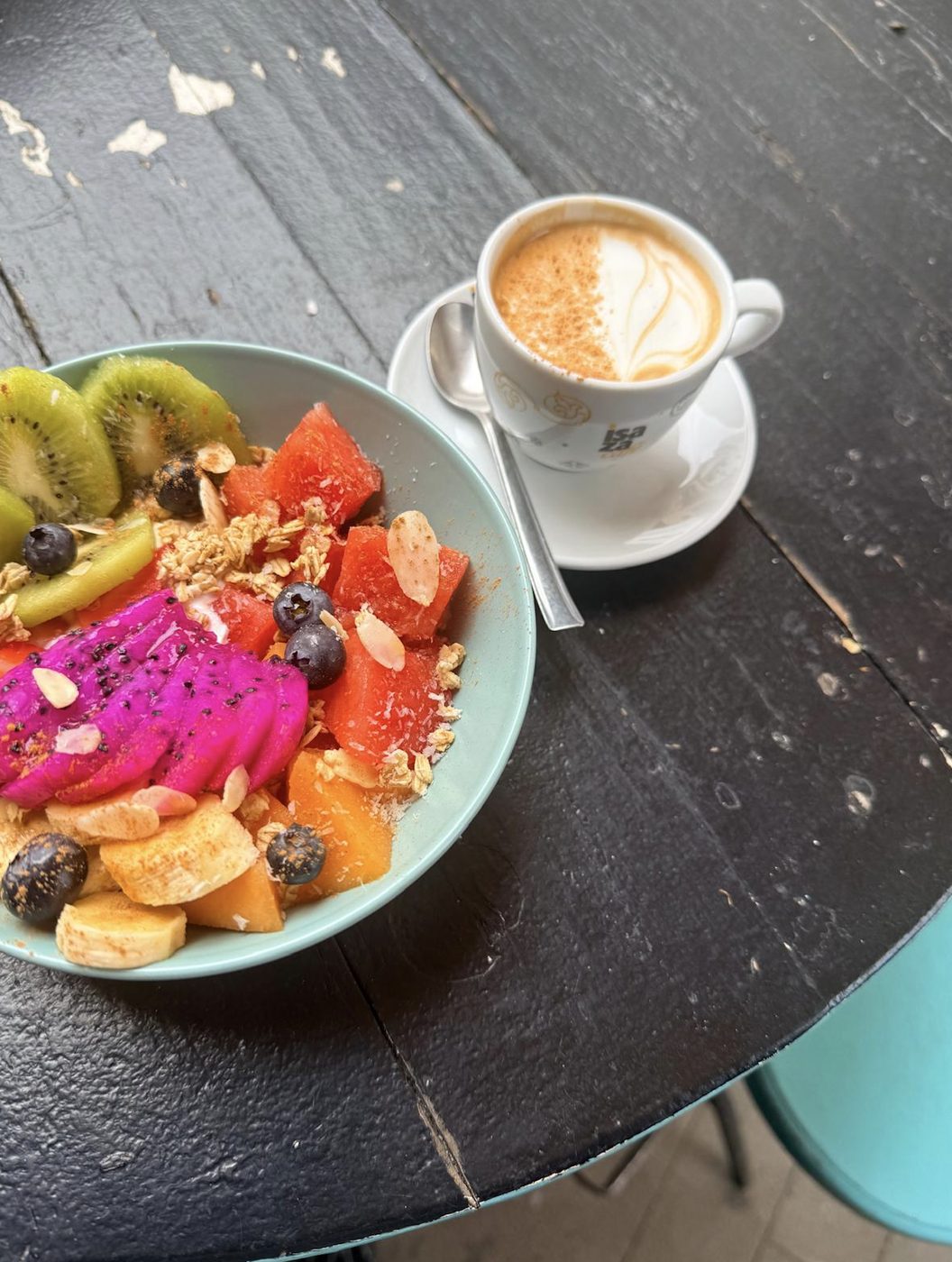 Bol de frutas con pitaya y granola, servido con un café